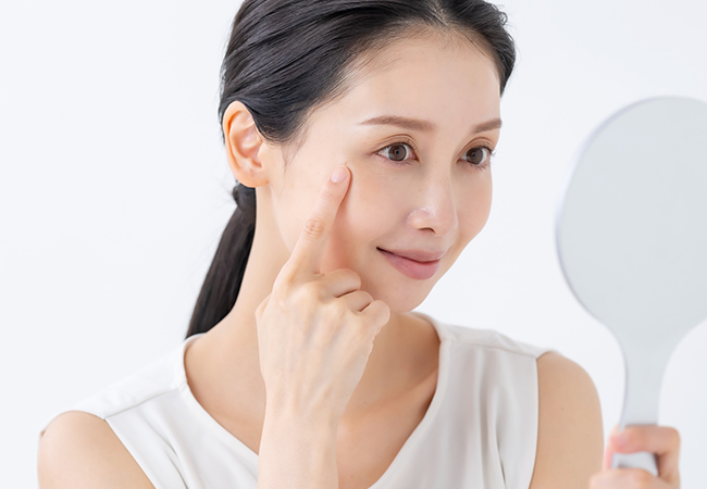 目元のハリを指でチェックする女性
